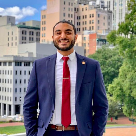 Shawn Soares, dressed in a suit, stands smiling.