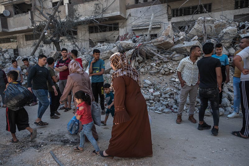 Palestinians walk past damaged buildings in al-Shati Refugee Camp west of Gaza City on May 15, 2021 in Gaza City, Gaza.