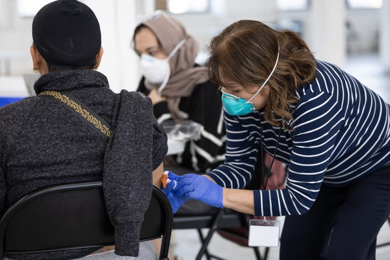 A worker with the Chicago Department of Public Health gives the measles-mumps-rubella vaccine to an individual at the migrant shelter for new arrivals in Pilsen.
