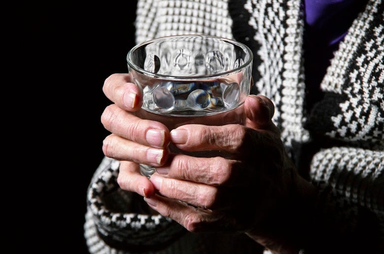 old woman holding glass of whisky 