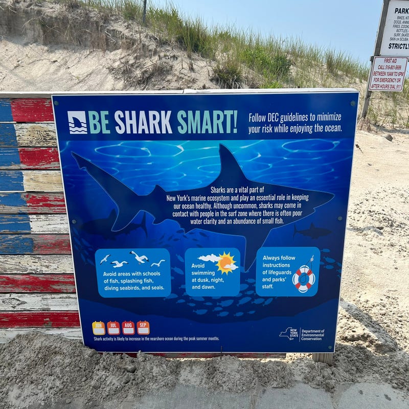 A sign reading "Be Shark Smart" is seen at Lido Beach on Tuesday following Monday's sighting