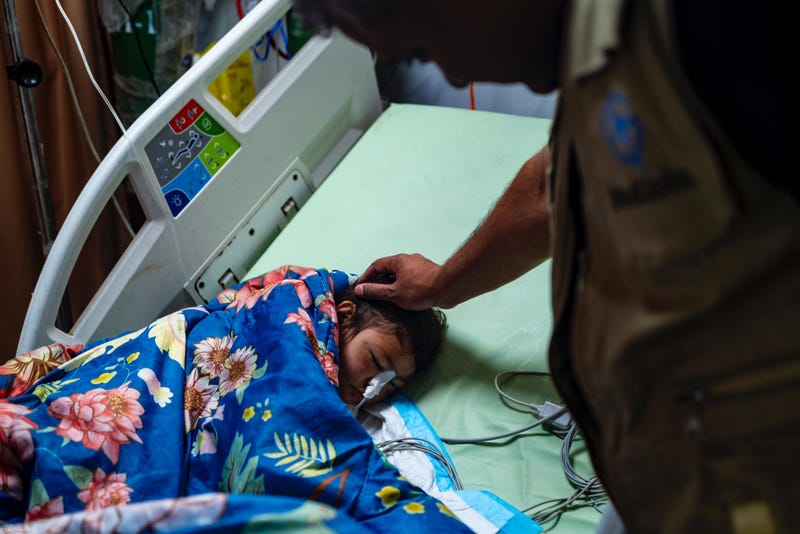 Dr. Syed Sayeed, a plastic surgeon from Long Island, strokes the head of a child patient during a volunteer trip to Gaza in April 2024.