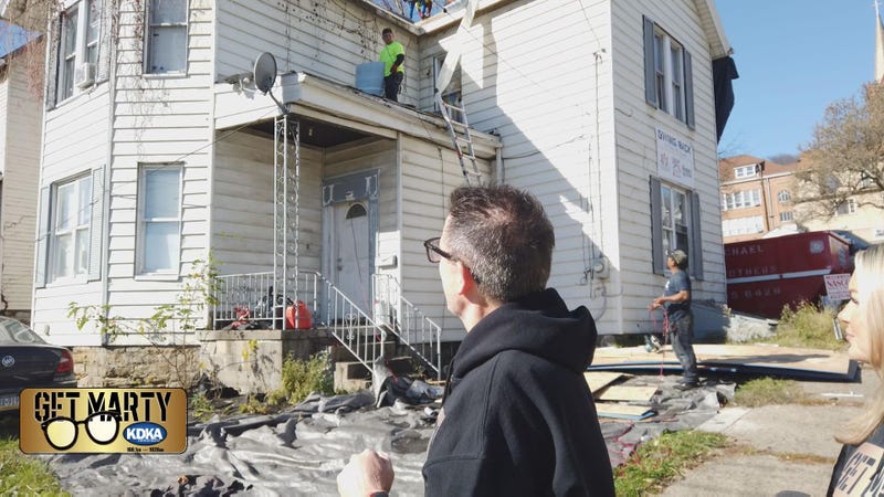 Marty Griffin and Arianna Bazzy look on as crews work to put the new roof on Kenneth's home.