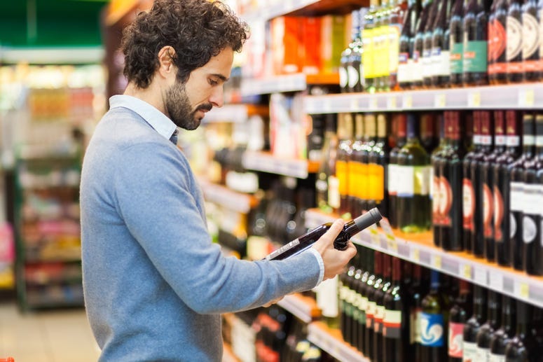 man checks price on wine bottle