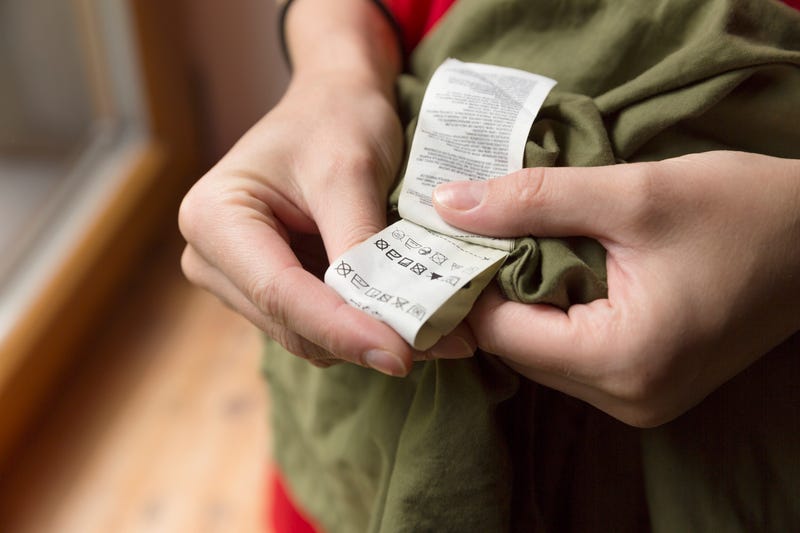 Close-up of person reading the clothing label showing washing instructions 