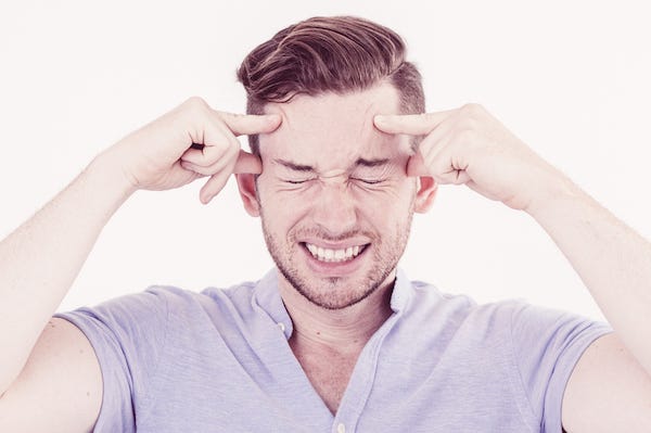 Man thinking hard and rubbing forehead