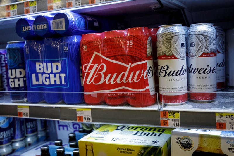 Cans of Budweiser and Bud Light sit on a shelf for sale at a convenience store.