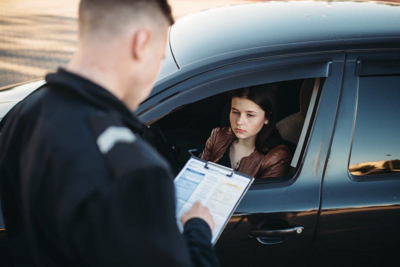 A woman receives a traffic ticket from a police officer