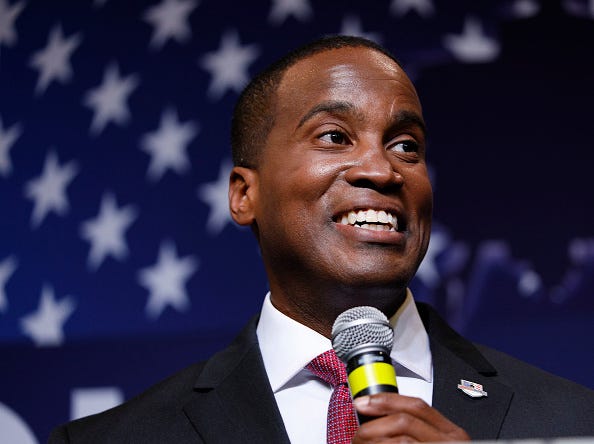 Senate candidate John James stands on stage holding a microphone
