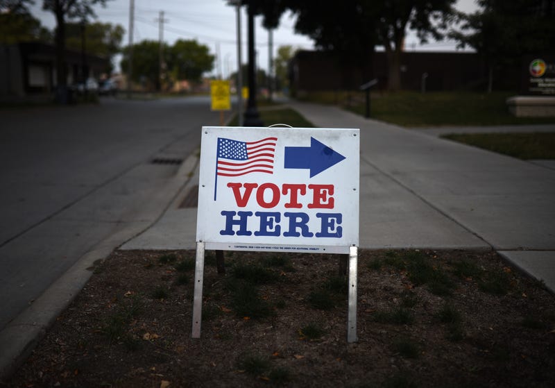 A sign reading "Vote Here" points toward a polling place for the 2018 primary election 