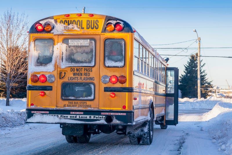 A typical yellow school bus stopped to pick up passengers on an extremly cold winter day.