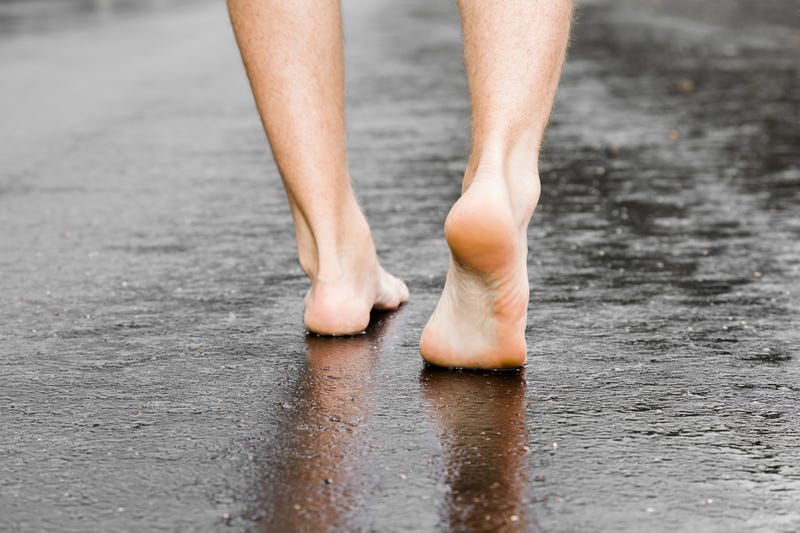 Man's barefoot on the street after rain.