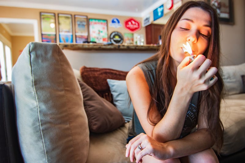 Young woman on couch lighting a joint