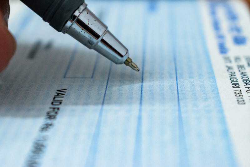 Pen poised over checkbook. 