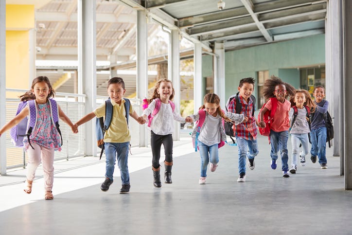 Elementary school kids run holding hands