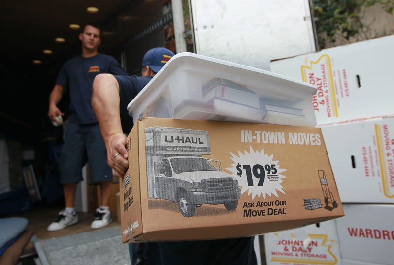 A worker with Johnson and Daly Moving and Storage carries boxes to a truck while moving a family.