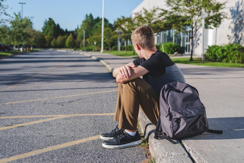 teenage boy sitting on curb