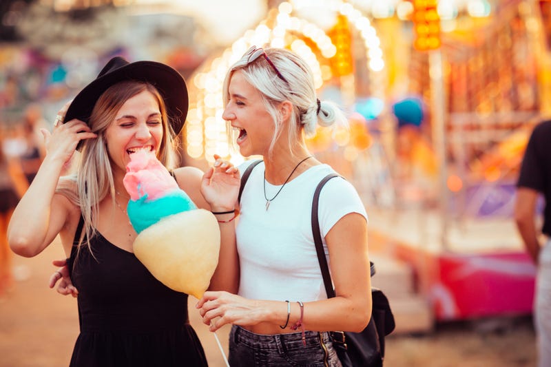 friends in amusement park eating cotton candy