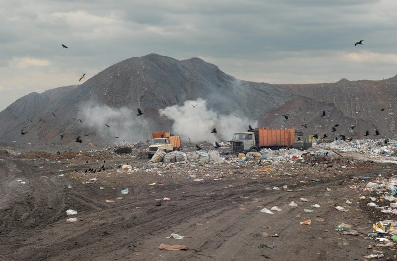 Garbage trucks on a city dump of dust - stock photo