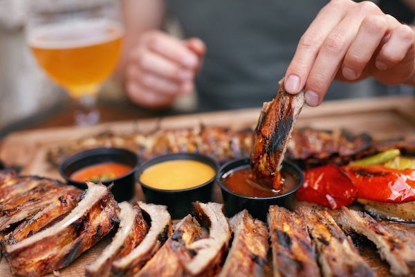 Man dipping a barbecue rib in sauce