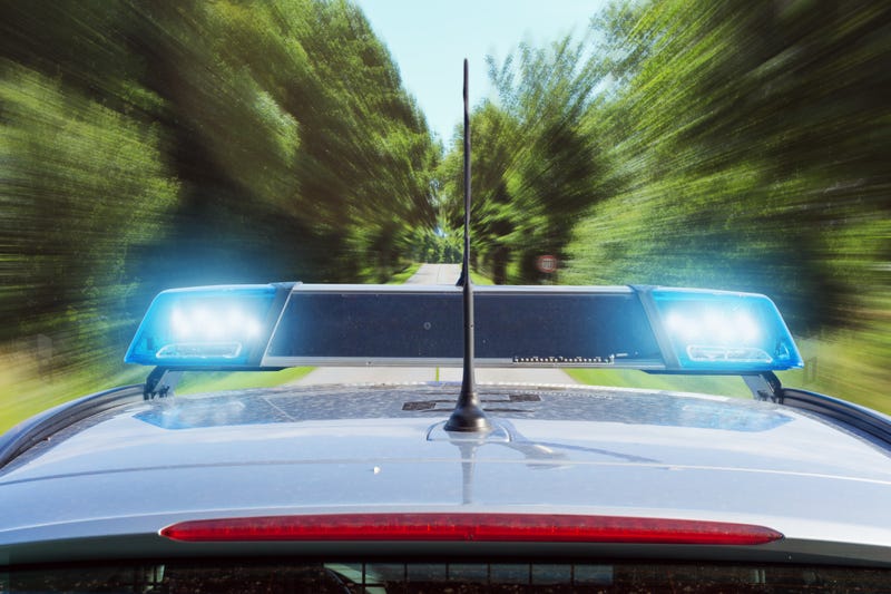 roof of a police car with flashing siren light s driving fast on a country road