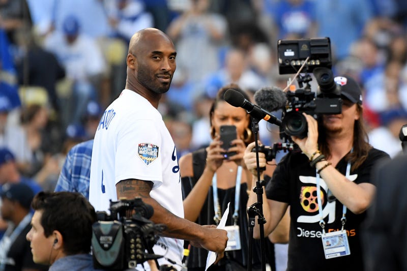 kobe bryant wearing a dodgers jersey in front of cameras at dodgers stadium