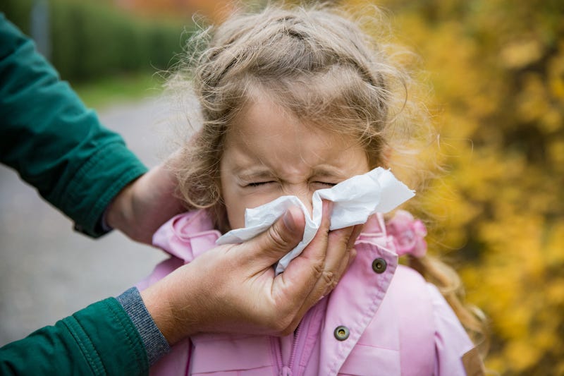 Father wipes daughter's nose with a tissue