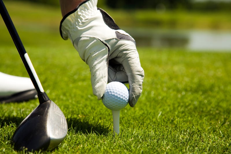 Hand places golf ball on tee