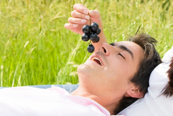 Man being fed grapes by a woman