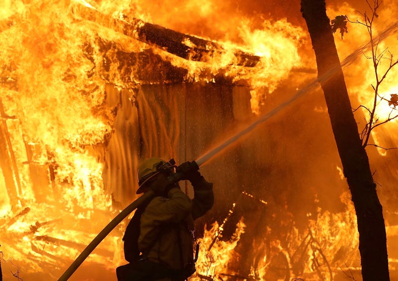 A Cal Fire firefighter monitors a burning home as the Camp Fire moves through the area on November 9, 2018 in Magalia, California.