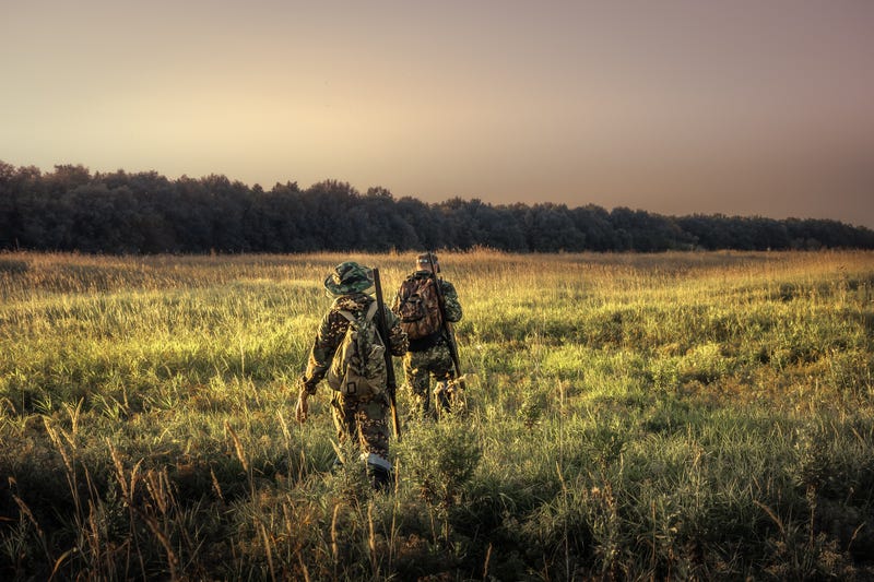 Father and son walking in field with hunting gear