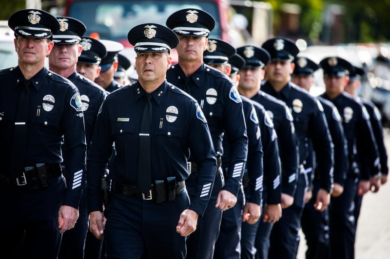 dozens of police officers walking in two lines