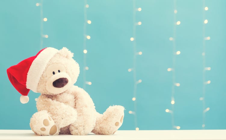 off-white Teddy bear wearing a Santa hat on a shiny light blue background