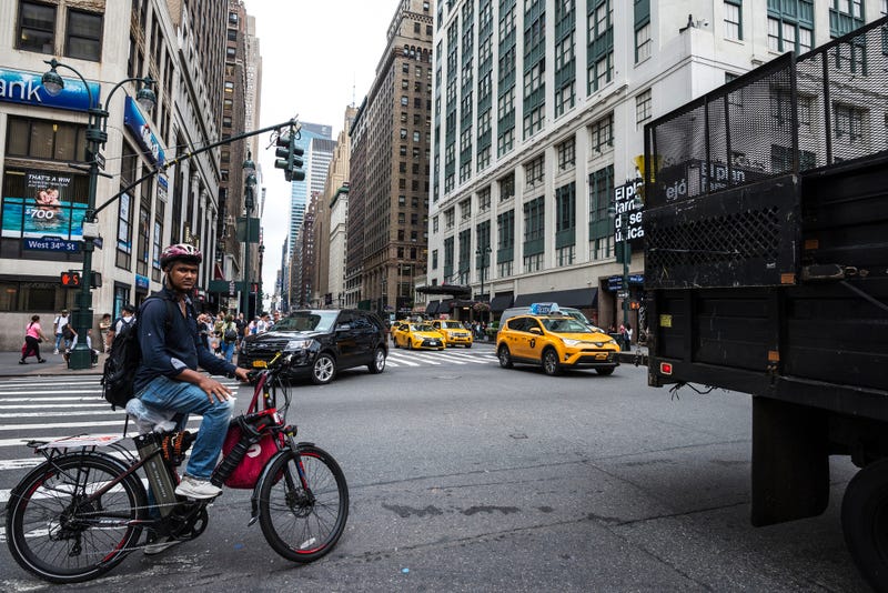 Seventh Avenue and 34th Street with a cyclist with an electric bike and people around in Manhattan in New York City, USA