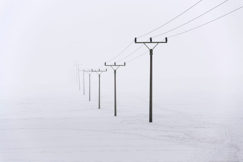 A snowy field with power lines stretching off to the distance