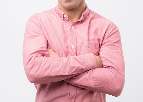 Man wearing a pink shirt with his arms crossed