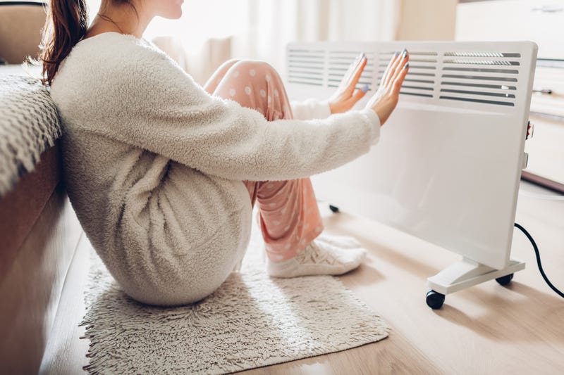 Woman warming her hands on heater