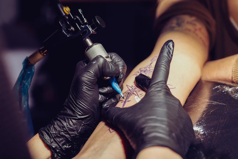 Tattoo artist tattooing arm