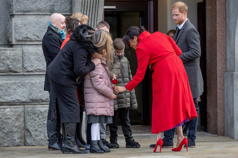 meghan markle and prince harry greet children outside as they visit a new statue to mark the 100th anniversary of the death of poet Wilfred Owen