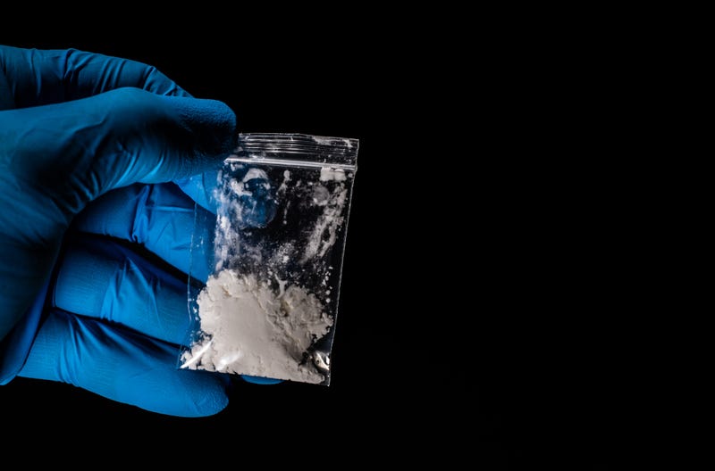 Gloved hand holding a bag of white powder. 