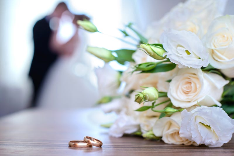 Wedding rings and bouquet on a background of blurred newlyweds