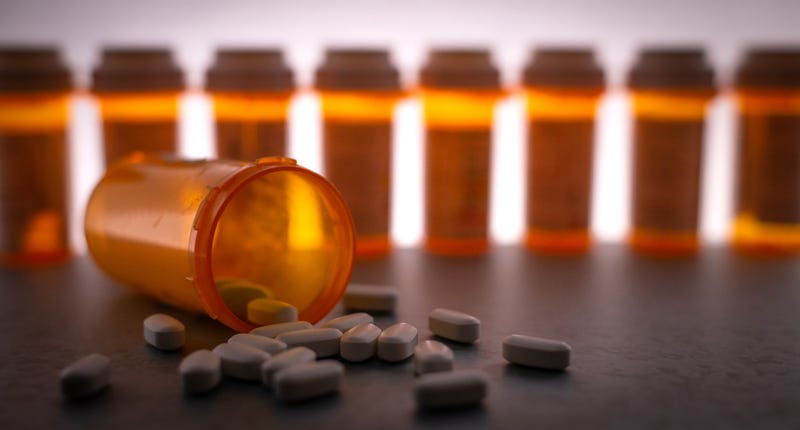 Fentanyl pills spilled out in front of prescription medication bottles. 