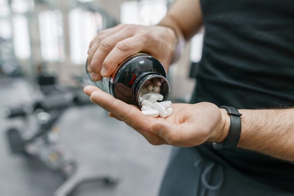 Muscular man emptying bottle of pills into his hand