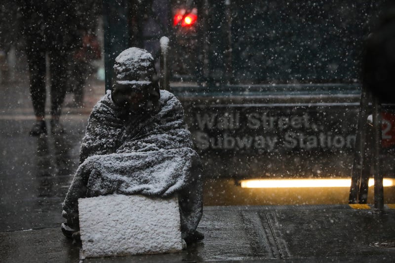 A homeless man sits in the falling snow in the Financial District, January 30, 2019 in New York City.