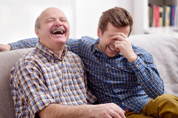 Father and son sitting on the couch laughing