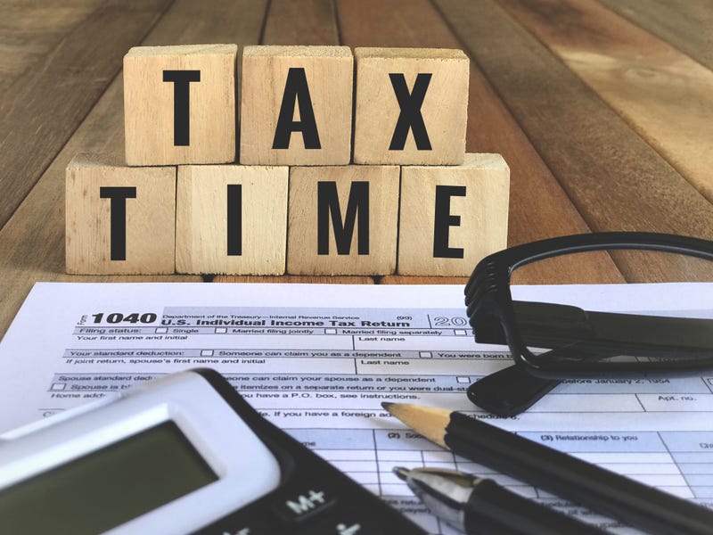 United States federal income tax return IRS 1040 documents, with pen, pencil, calculator, eyeglasses and wooden blocks with ‘TAX TIME’ written on them.