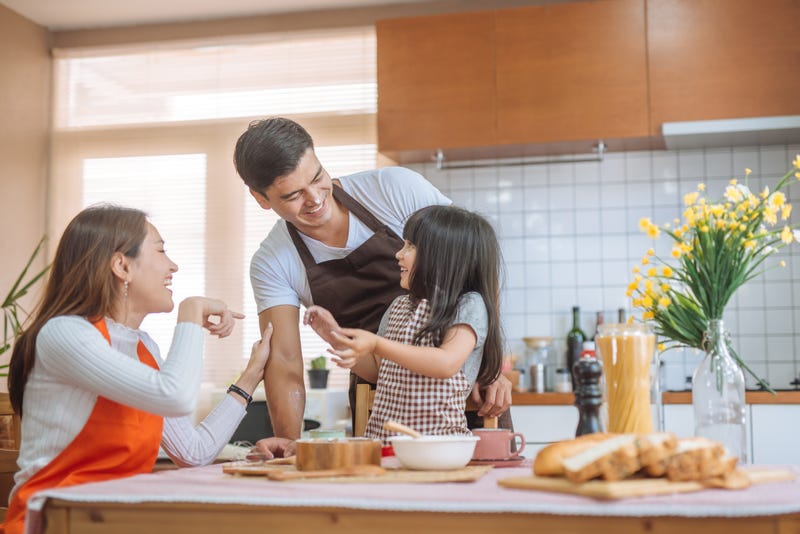 Parents and a young daughter fool around while cooking