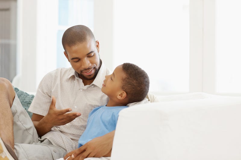 A father and son talk on a couch