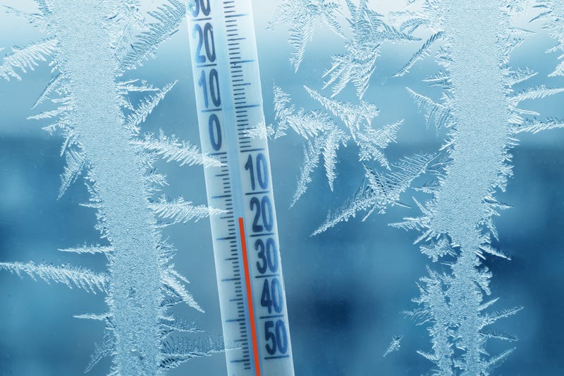 Frosty winter window with ice patterns and a thermometer showing a minus temperature