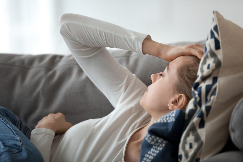 Woman on couch feeling ill. 